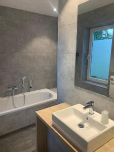 a bathroom with a white sink and a bath tub at RAVeL Hotel Cyrano in Waimes