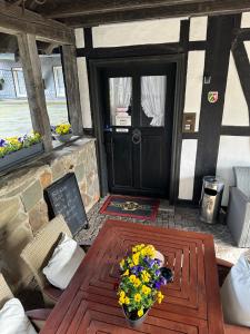 a wooden table with flowers on it in front of a door at Hotel zur Post Dabringhausen - contactless self check-in in Wermelskirchen
