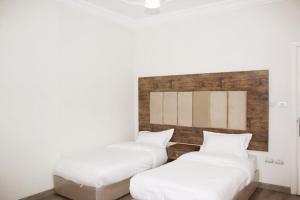 two beds in a room with white walls at كيان المكرونة للشقق المخدومة - Kayan Al-Makaruna Serviced Apartments in Jeddah