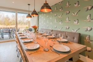 a dining room with a long table with chairs and birds on the wall at Goslings in Somerford Keynes