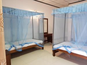2 camas en una habitación con cortinas azules en Yala Beach Resort, en Kirinda