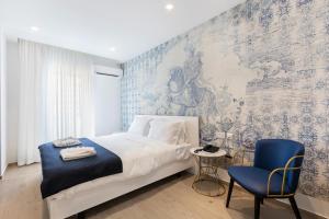 sypialnia z łóżkiem i niebieskim krzesłem w obiekcie The G Hotel by JL w mieście St. Julian’s