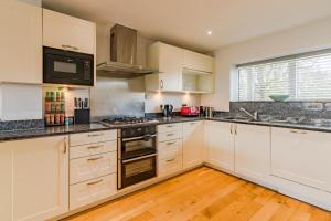 a kitchen with white cabinets and black counter tops at Goslings in Somerford Keynes