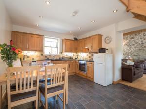 a kitchen with a table and a white refrigerator at Briallen Llanrhystud in Llanrhystyd