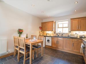 a kitchen with wooden cabinets and a wooden table and chairs at Briallen Llanrhystud in Llanrhystyd