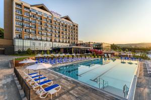 a hotel with a pool with chairs and umbrellas at Movenpick Resort and Spa Fruske Terme in Vrdnik +198 photos
