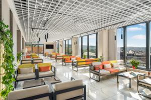a waiting room with chairs and tables and windows at Movenpick Resort and Spa Fruske Terme in Vrdnik