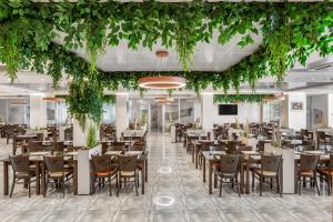 a dining room with tables and chairs and plants at Movenpick Resort and Spa Fruske Terme in Vrdnik