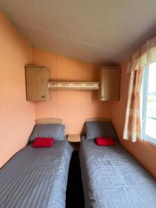 2 Betten in einem kleinen Zimmer mit Fenster in der Unterkunft Spacious 2 bedroomed mobile home in Aberystwyth
