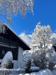 ein schneebedecktes Haus neben einem Baum in der Unterkunft Ferienwohnung Theresia in Garmisch-Partenkirchen