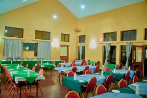 une salle remplie de tables et de chaises avec des tables vertes et rouges dans l'établissement NGORONGORO CORRIDOR LODGE Karatu, à Karatu