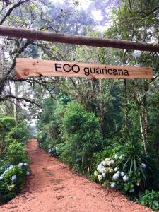una señal que dice ecoco guatemala colgando sobre un camino de tierra en Bosque Contêiner Eco Guaricana en São José dos Pinhais