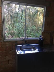 a kitchen sink in front of a window at Bosque Contêiner Eco Guaricana in São José dos Pinhais