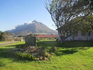 a sign in the grass with a mountain in the background at Lighthouse Farm Backpackers Lodge in Cape Town