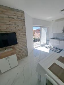 a white living room with a tv on a brick wall at Apartmani Totić in Malinska