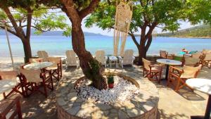 una mesa con sillas y un árbol en la playa en Klima Paradise, en Klíma