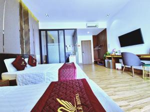 um quarto de hotel com duas camas e uma televisão de ecrã plano em THƯ LÊ Hotel em Cao Lãnh