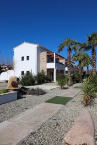 a white house with palm trees in front of it at Résidence La Dolce Vita in Ghisonaccia