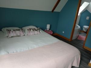 1 dormitorio con cama blanca y pared azul en La Cave "La Villa Saint Martin" en Pontorson