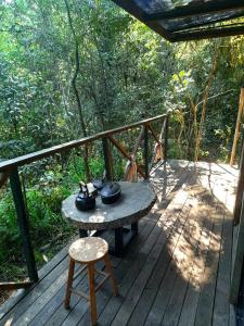 a table and a chair on a wooden deck at Bosque Contêiner Eco Guaricana in São José dos Pinhais