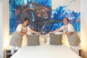 dwie kobiety stoją obok łóżka w obiekcie Art Hotel Principe w Lignano Sabbiadoro