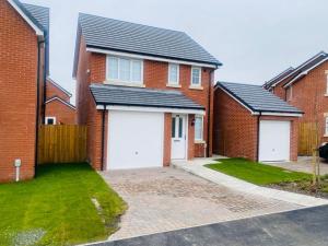 a row of brick houses with white garage doors at Brand New 3 Bedrooms Detached House in Westhoughton