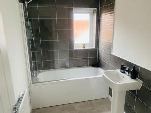 a bathroom with a bath tub and a sink at Brand New 3 Bedrooms Detached House in Westhoughton