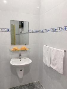 ein Badezimmer mit einem Waschbecken, einem Spiegel und Handtüchern in der Unterkunft Nhà Nghỉ Tấn Phát in Ấp Thanh Sơn (1)