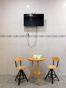 un tavolo e due sgabelli con una tv a muro di Nhà Nghỉ Tấn Phát a Ấp Thanh Sơn (1)