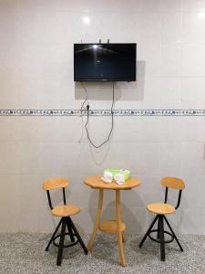 un tavolo e due sgabelli con una tv a muro di Nhà Nghỉ Tấn Phát a Ấp Thanh Sơn (1)