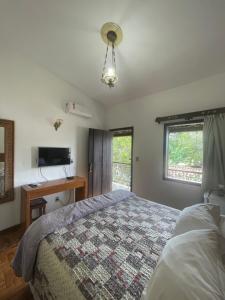 a bedroom with a bed and a desk and a window at Pousada das Artes in Tiradentes