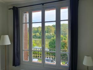 een raam met uitzicht op een meer bij EXIGEHOME - Grande maison en bord d'étang à 20 min de Paris in Vélizy-Villacoublay
