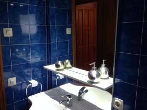 Baño de azulejos azules con lavabo y espejo en GLORIA apartament NEAR THE BEACH en Can Picafort