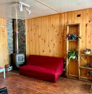 CABAÑA CON MUELLE ORILLA LAGUNA في كيلون: غرفة معيشة مع أريكة حمراء وتلفزيون