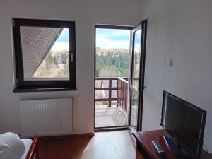 een kamer met een televisie en een balkon met uitzicht bij Rusticanna in Ranca