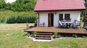 a house with a wooden deck with a table and chairs at Mogielicki Zakątek in Jurków