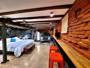 1 dormitorio con cama y pared de ladrillo en Maki Hostels & Suites Valparaiso, en Valparaíso