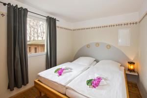ユッケリッツにあるOstseeperle - 60730のベッドルーム1室(白いシーツと紫の花のベッド1台付)