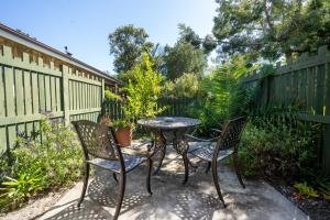 d'une terrasse avec une table, deux chaises et une clôture. dans l'établissement Forest Cove cottage, à Knysna