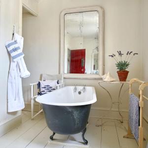 eine Badewanne im Bad mit Spiegel in der Unterkunft Mariner's Cottage by Coaste in Deal
