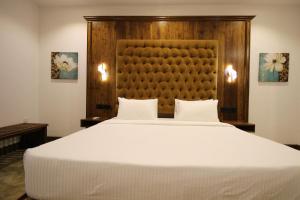 a bedroom with a large white bed with a wooden headboard at Hotel Refresh Blue in Hikkaduwa