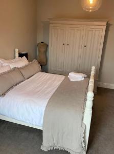 a bedroom with a large white bed and a cabinet at Sherwood House in Matlock