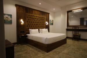 a bedroom with a large bed with a wooden headboard at Hotel Refresh Blue in Hikkaduwa