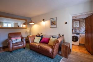 a living room with a leather couch and a chair at Cosy Matlock Cottage with Fireplace, Stunning Views & Pet Friendly in Two Dales