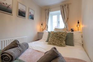 a bedroom with a white bed with pillows and a window at Cosy Matlock Cottage with Fireplace, Stunning Views & Pet Friendly in Two Dales