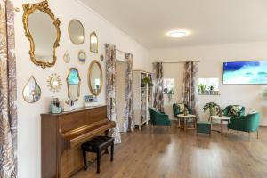 ein Wohnzimmer mit einem Klavier und grünen Stühlen in der Unterkunft Garden Hotel Primavera in Brissago