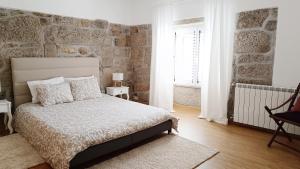 a bedroom with a bed and a stone wall at Casa do Sobrado ByAlta in Caparrosa