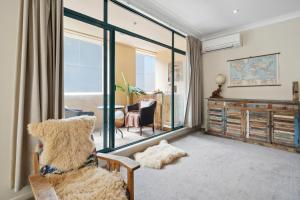 a living room with a large window and a chair at The Urban Charmer - Wellington Holiday Apartment in Wellington