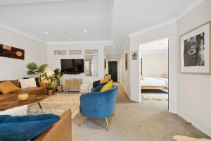 sala de estar con silla azul y sofá en The Urban Charmer - Wellington Holiday Apartment, en Wellington