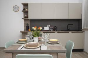 una cocina con una mesa de madera con platos y vasos. en Nuovo Appartamento in Pieno Centro con WiFi E Clima, en Civitanova Marche